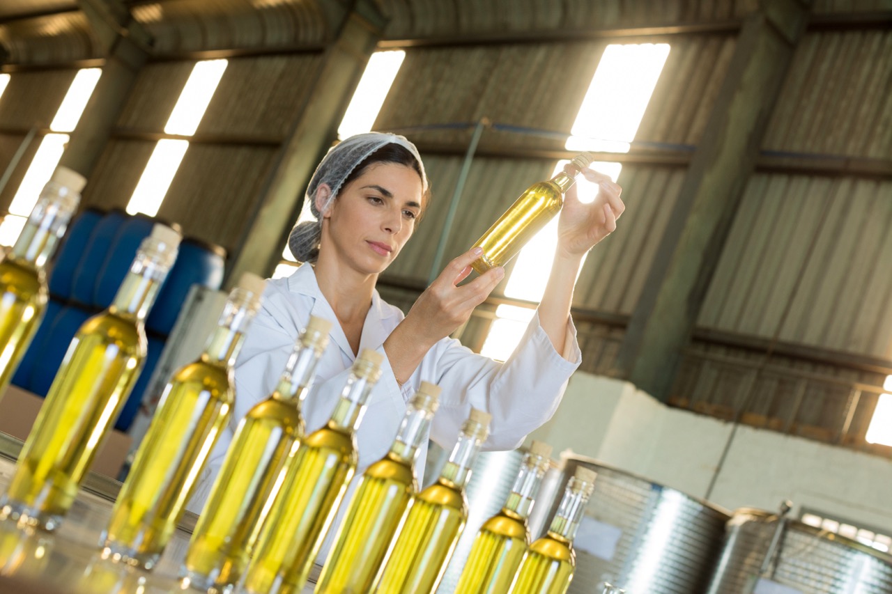 Technician examining olive oil in factory